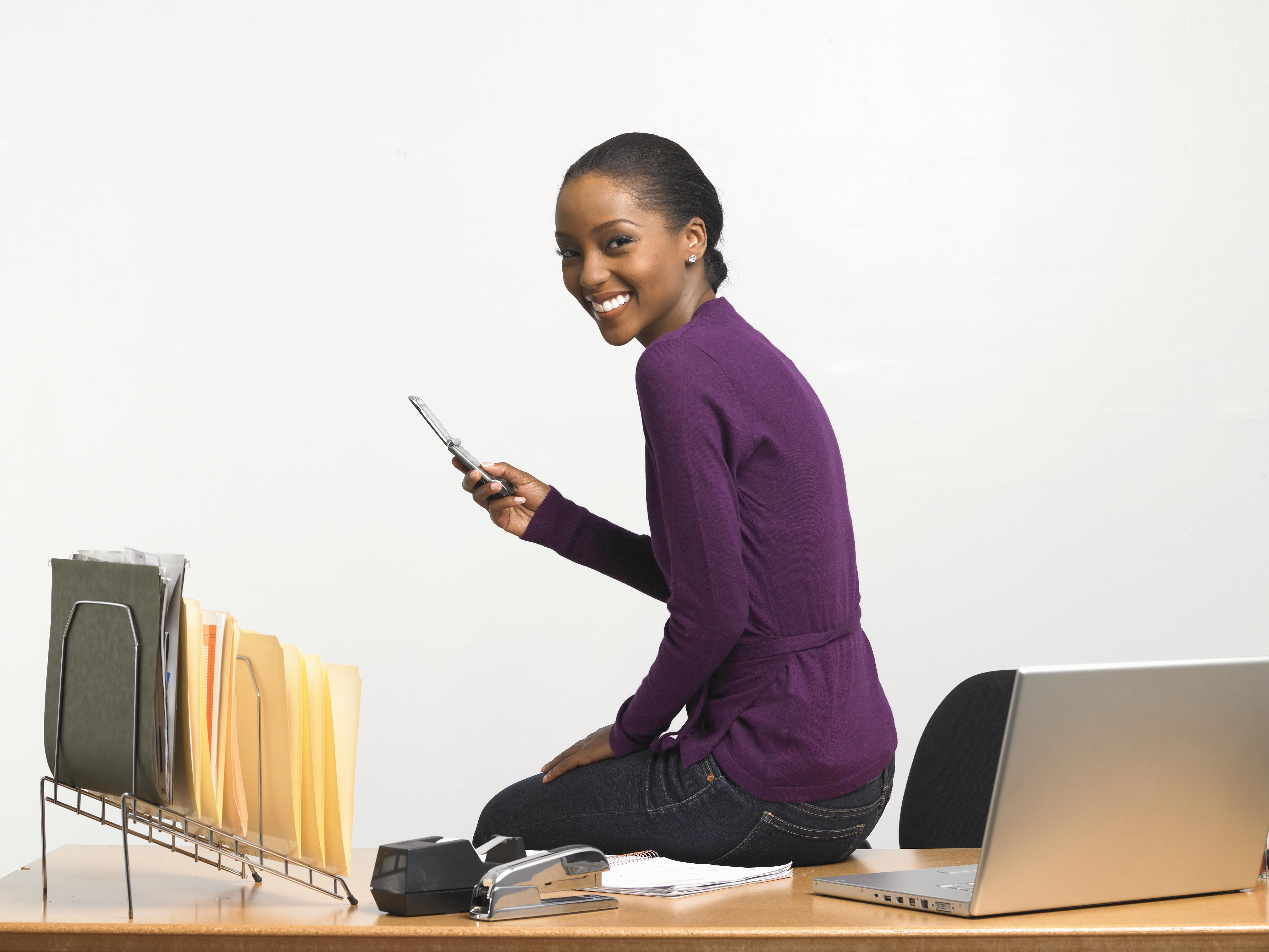Young woman with cell phone sitting on desk